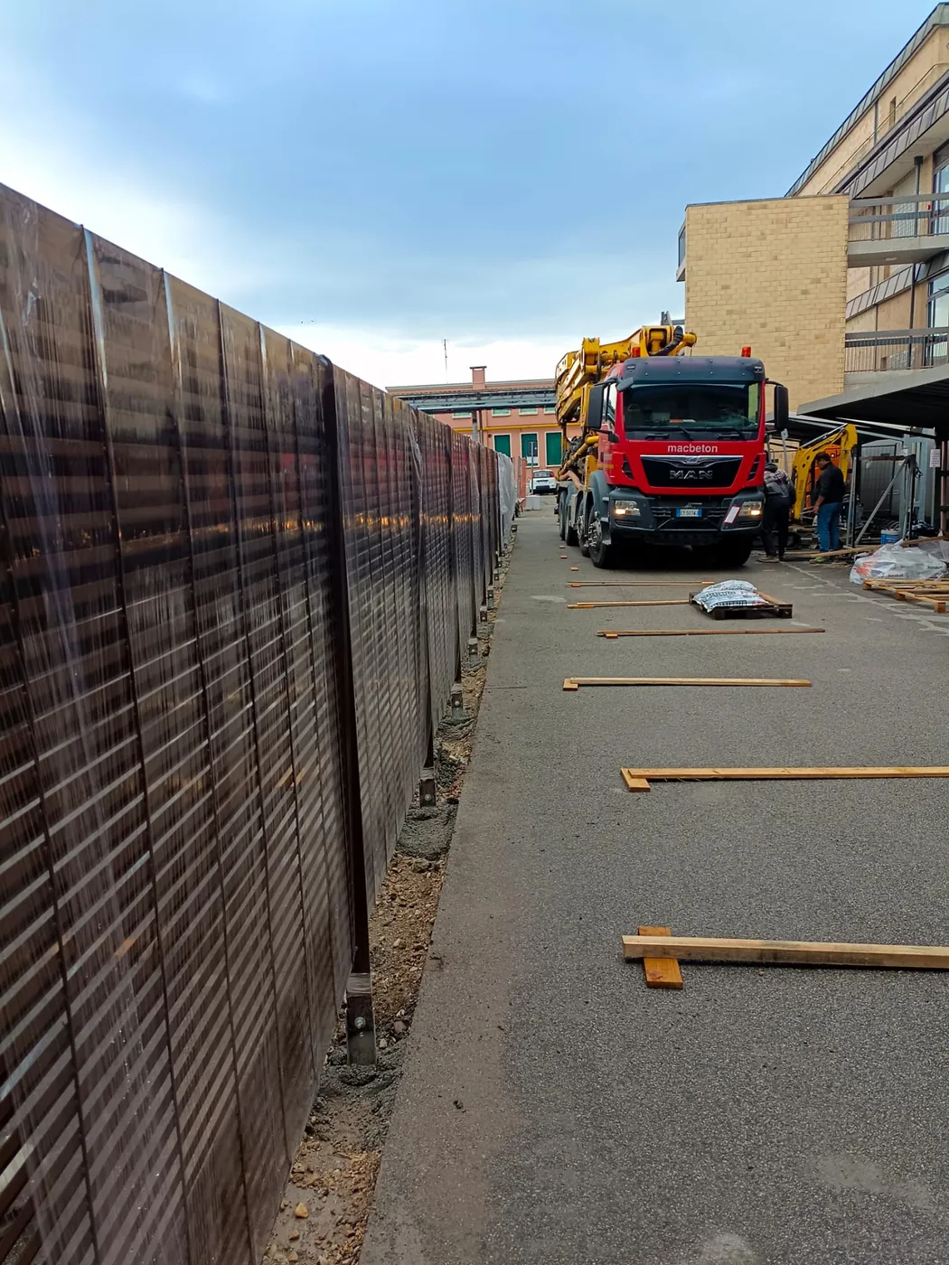 Recinzione in grigliato lungo il percorso, con un camion in fondo