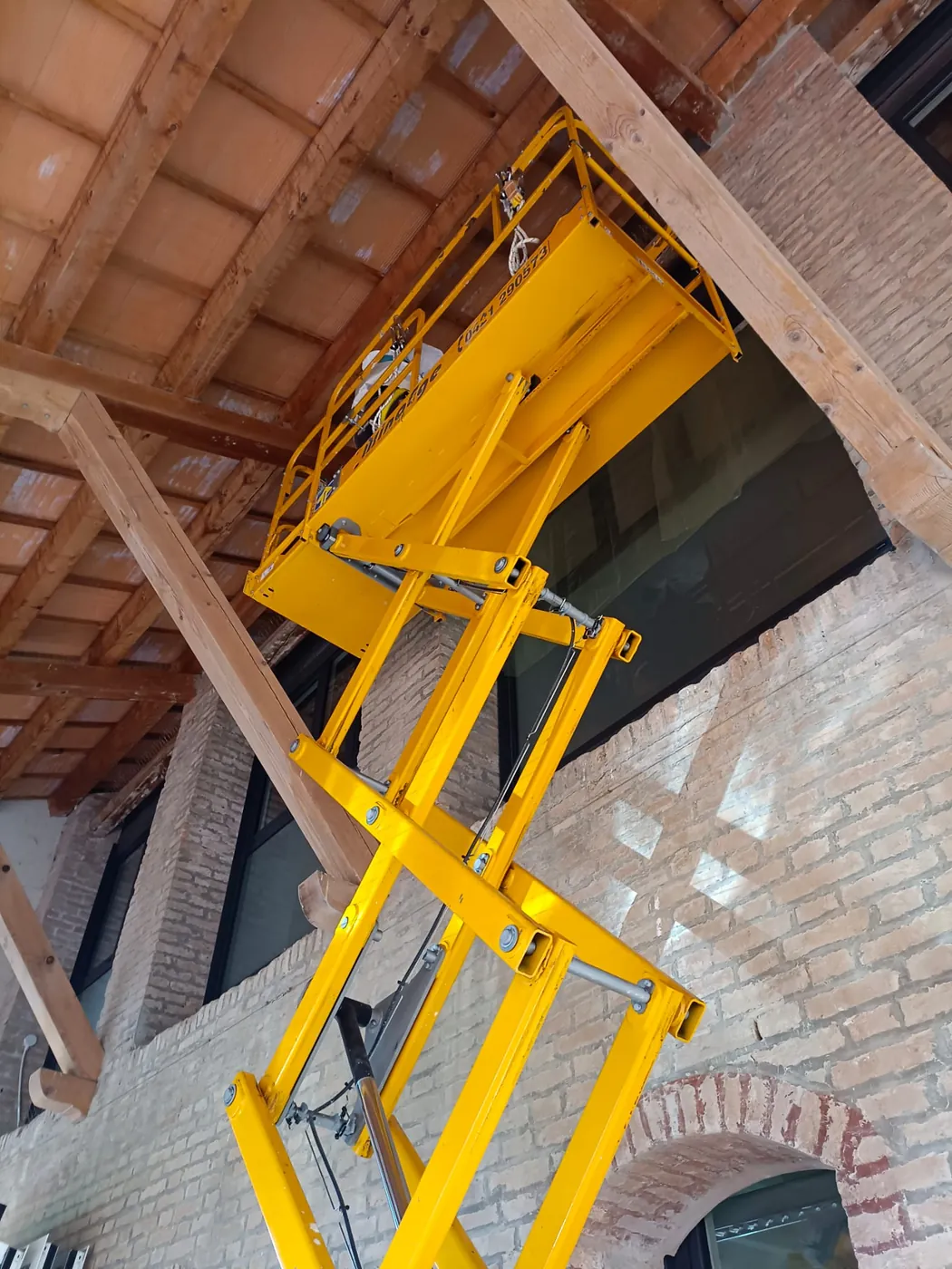 Piattaforma elevatrice gialla davanti alle finestre alte