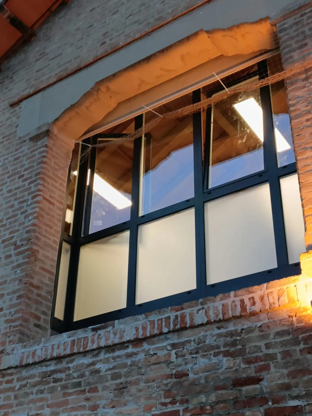 Finestra nuova in un'apertura in mattoni, illuminata di sera