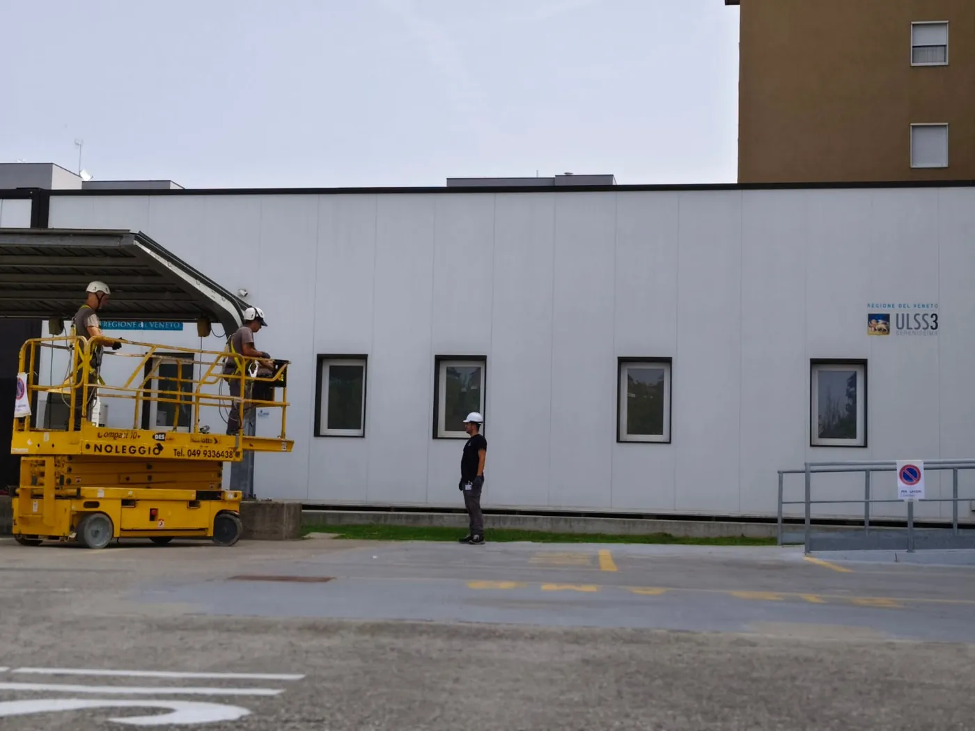 Due operai sulla piattaforma, al lavoro sulla parete del modulo