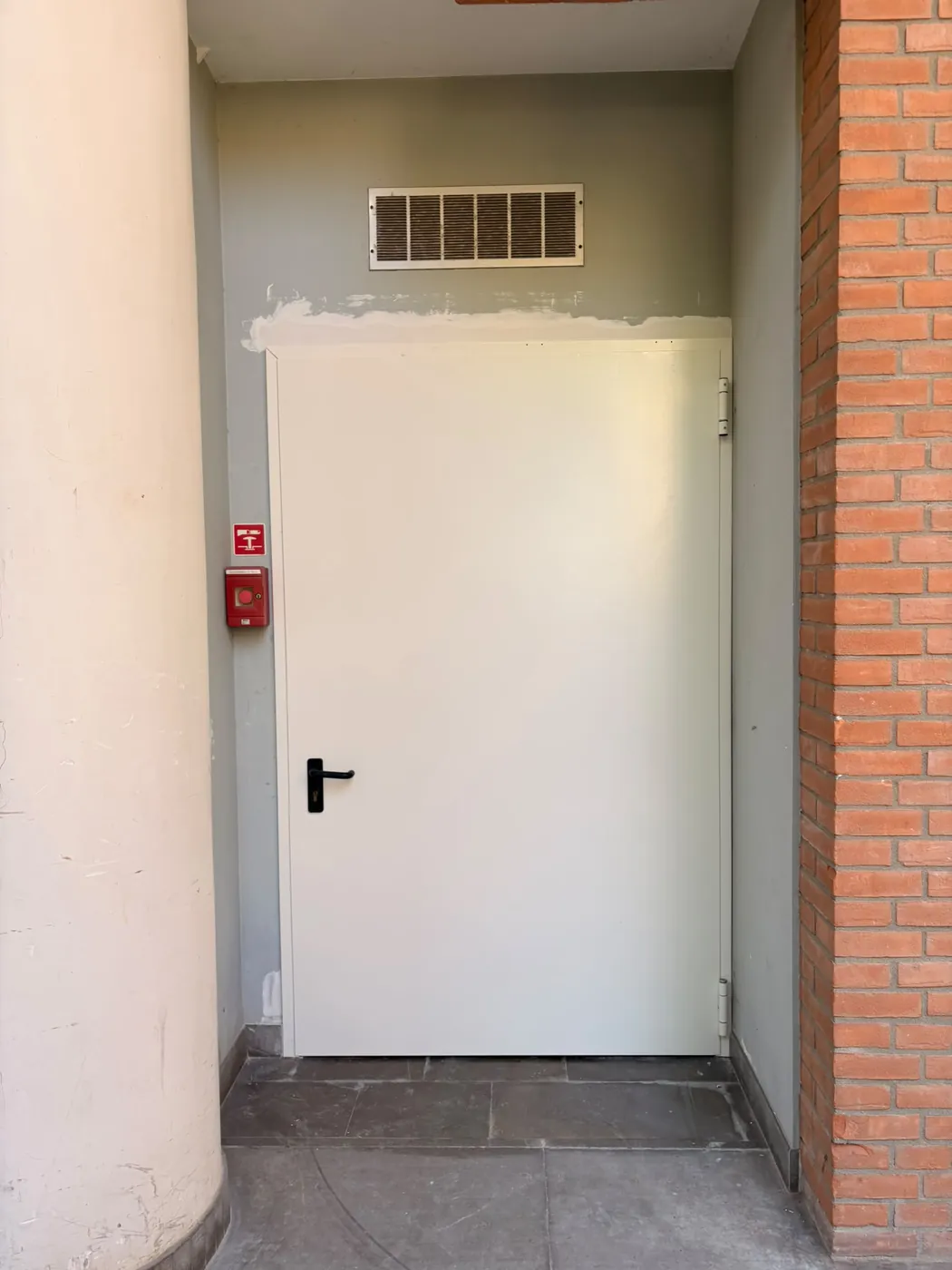 Porta a un'anta in un passaggio, con il muro appena ripreso sopra